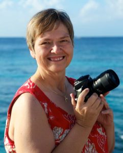 Kat Ramage holding camera with ocean in background in Grand Cayman